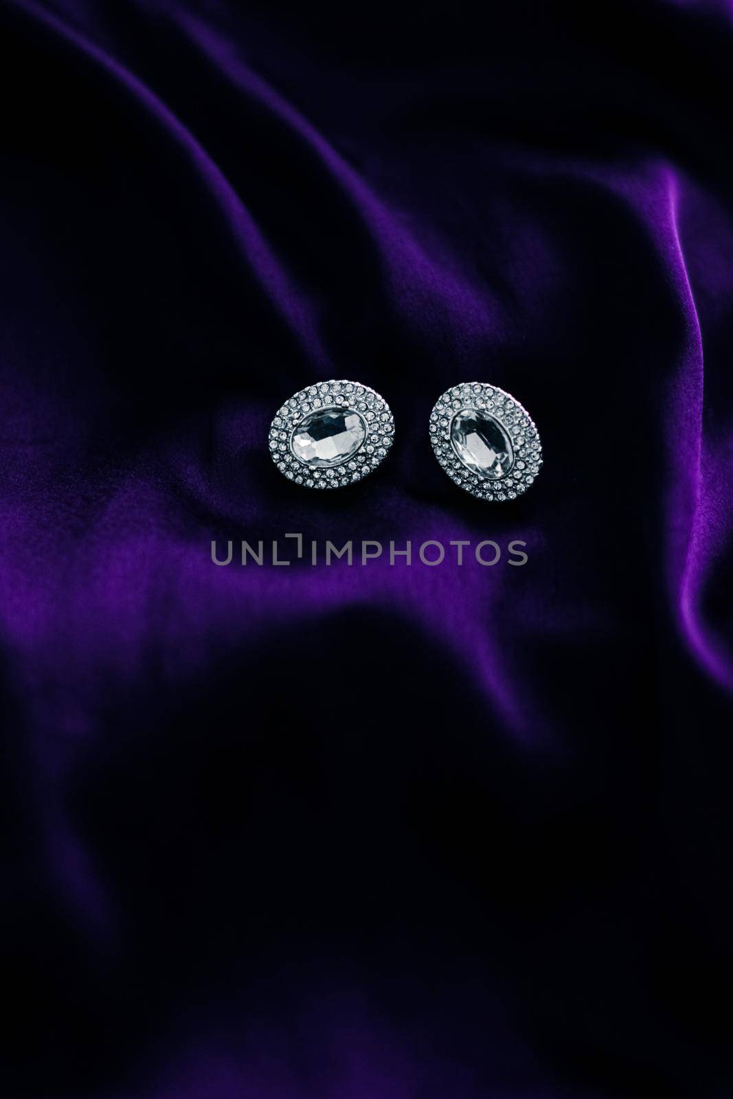 Luxury diamond earrings on dark violet silk fabric, holiday glamour jewelery present by Anneleven