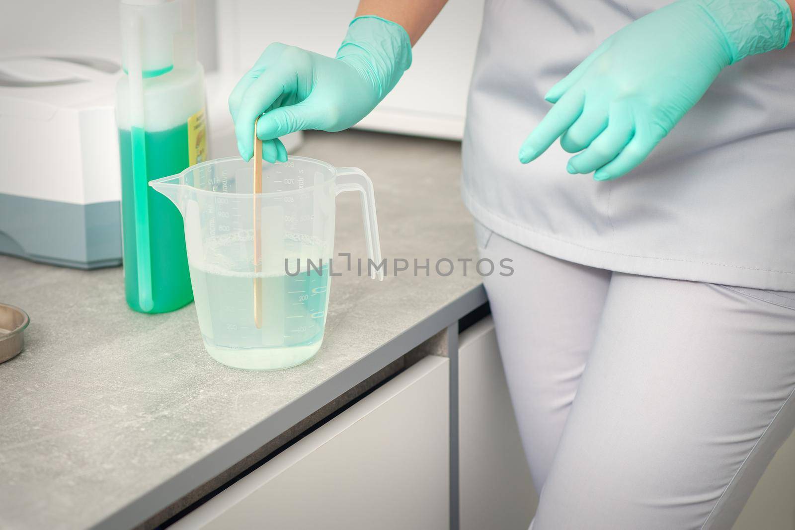 The beautician uses a stick to mix disinfectant into the water. Sterilization of tools