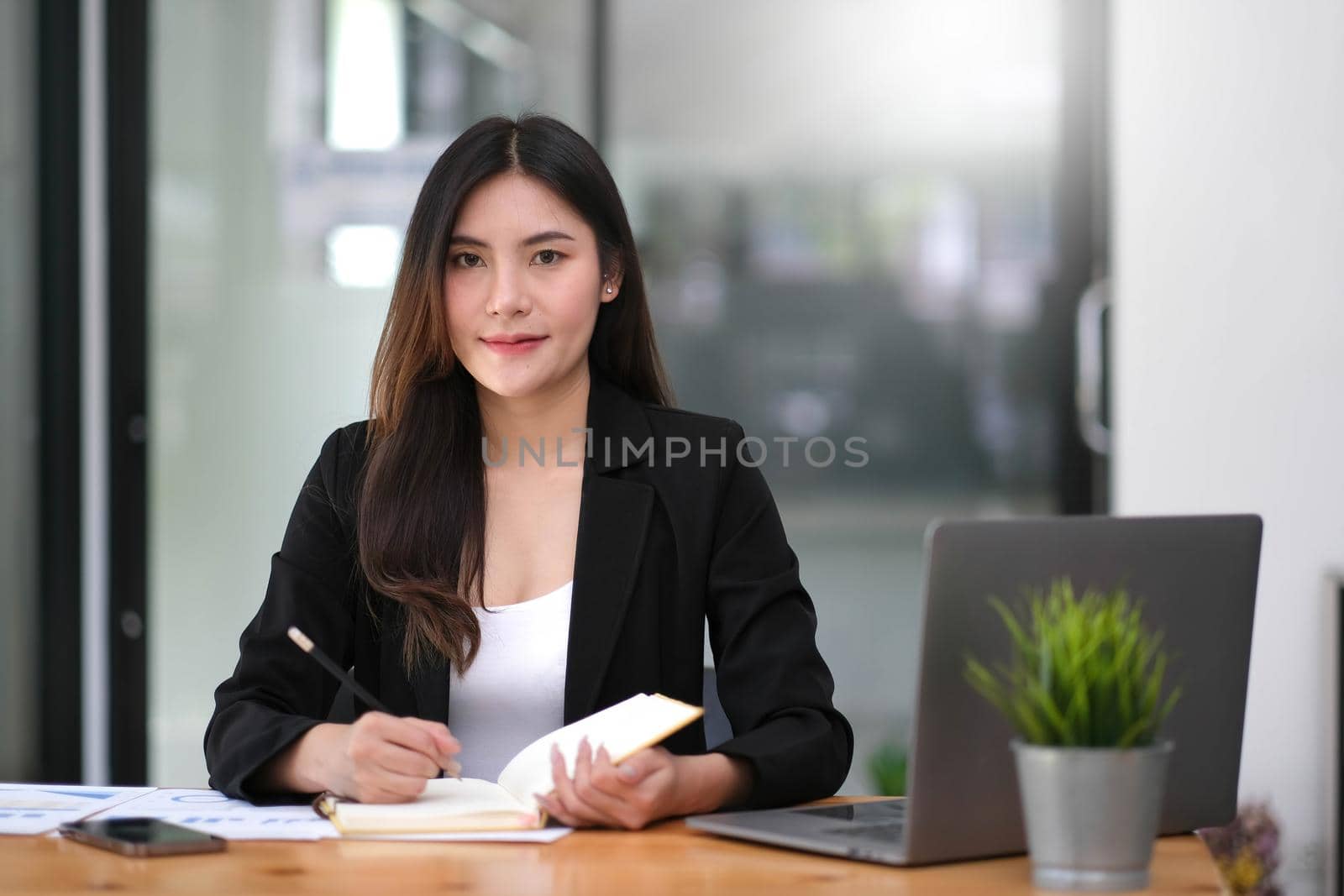 Pretty and charming asian businesswoman sitting happily smiling with laptop computer in the office. by wichayada