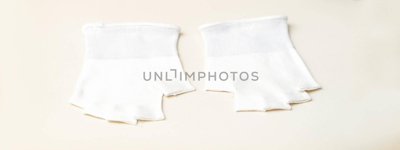 White bamboo fingerless inner gloves for cosmetic procedures lying on white. by okskukuruza