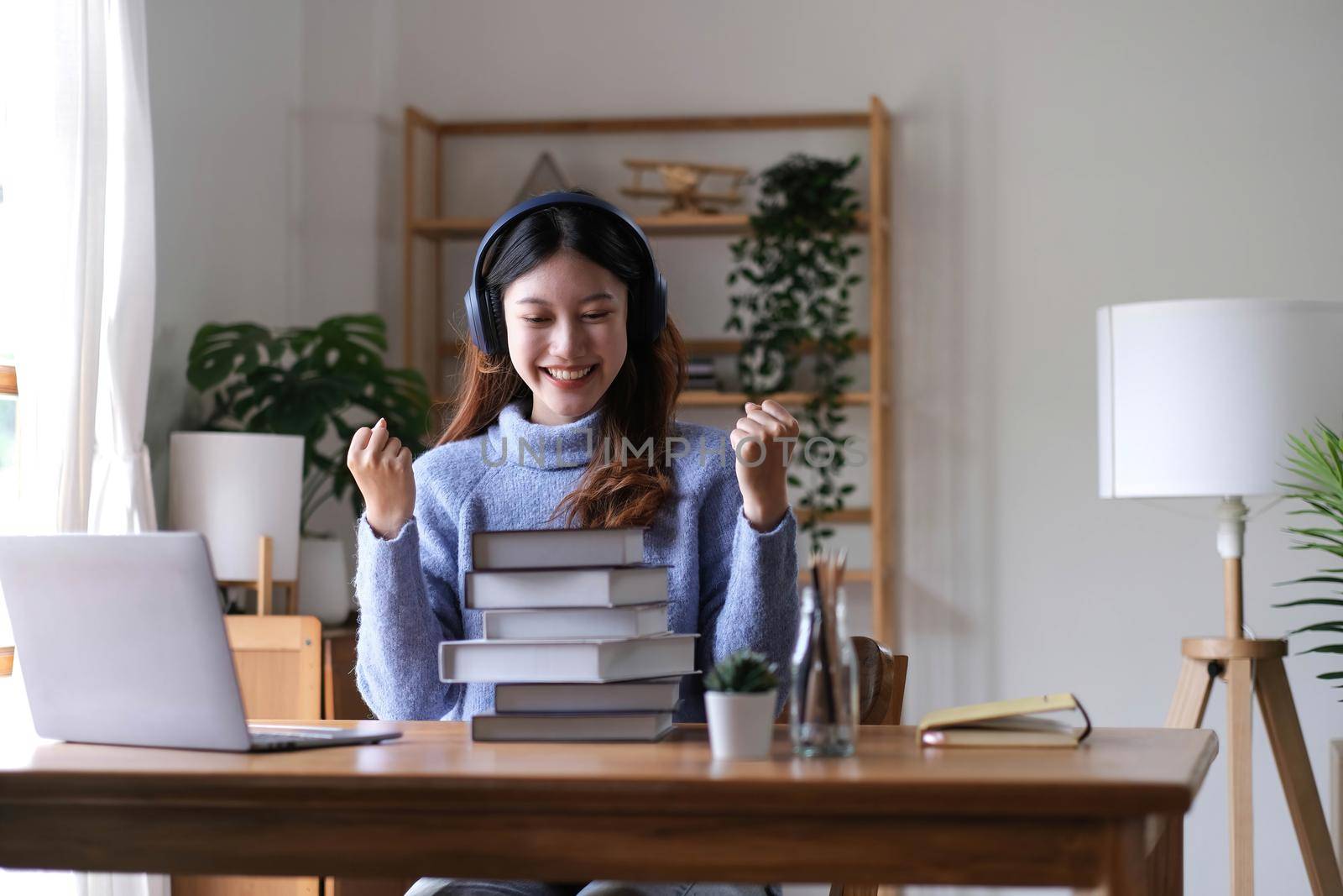 Asian woman celebrate with laptop, success happy pose. E-commerce, University education, internet Technology, or startup small business concept. Modern office or living room with copy space.