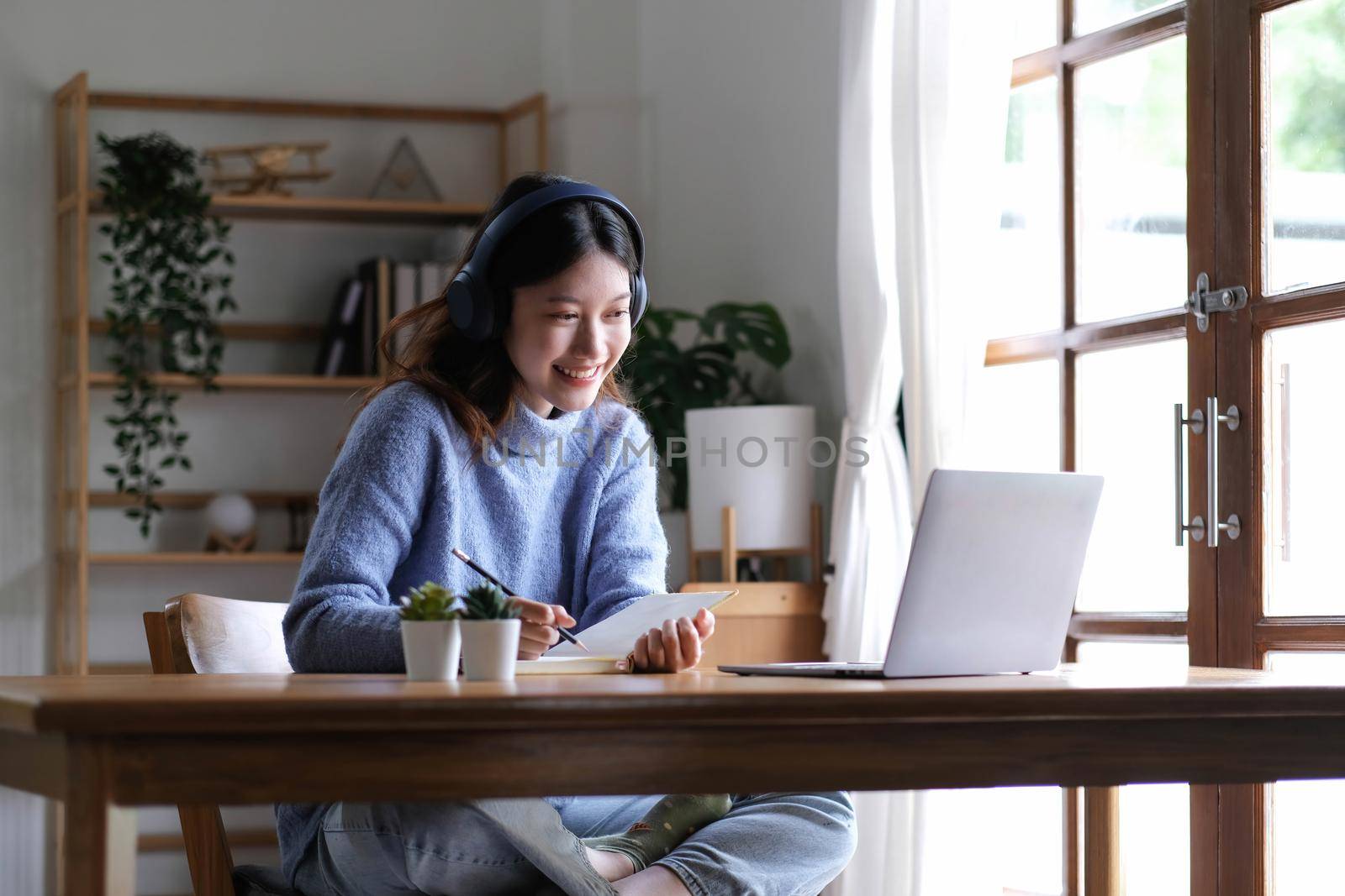 A young Asian university student wearing headphones to study online at home,During the time of the virus outbreak and did not attend university..
