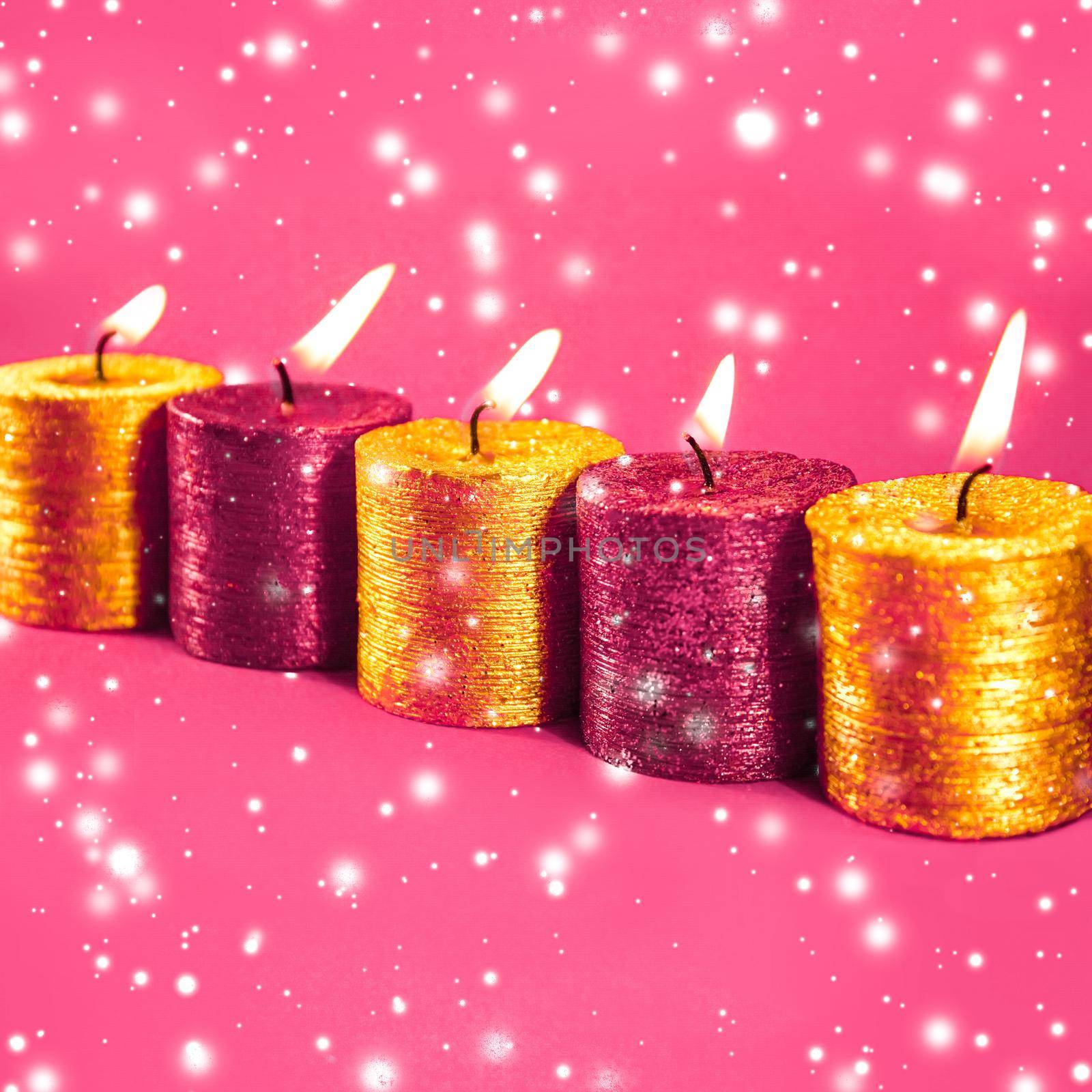 Winter, celebration and new years eve concept - Christmas candles and shiny snow on pink background, holiday season decoration