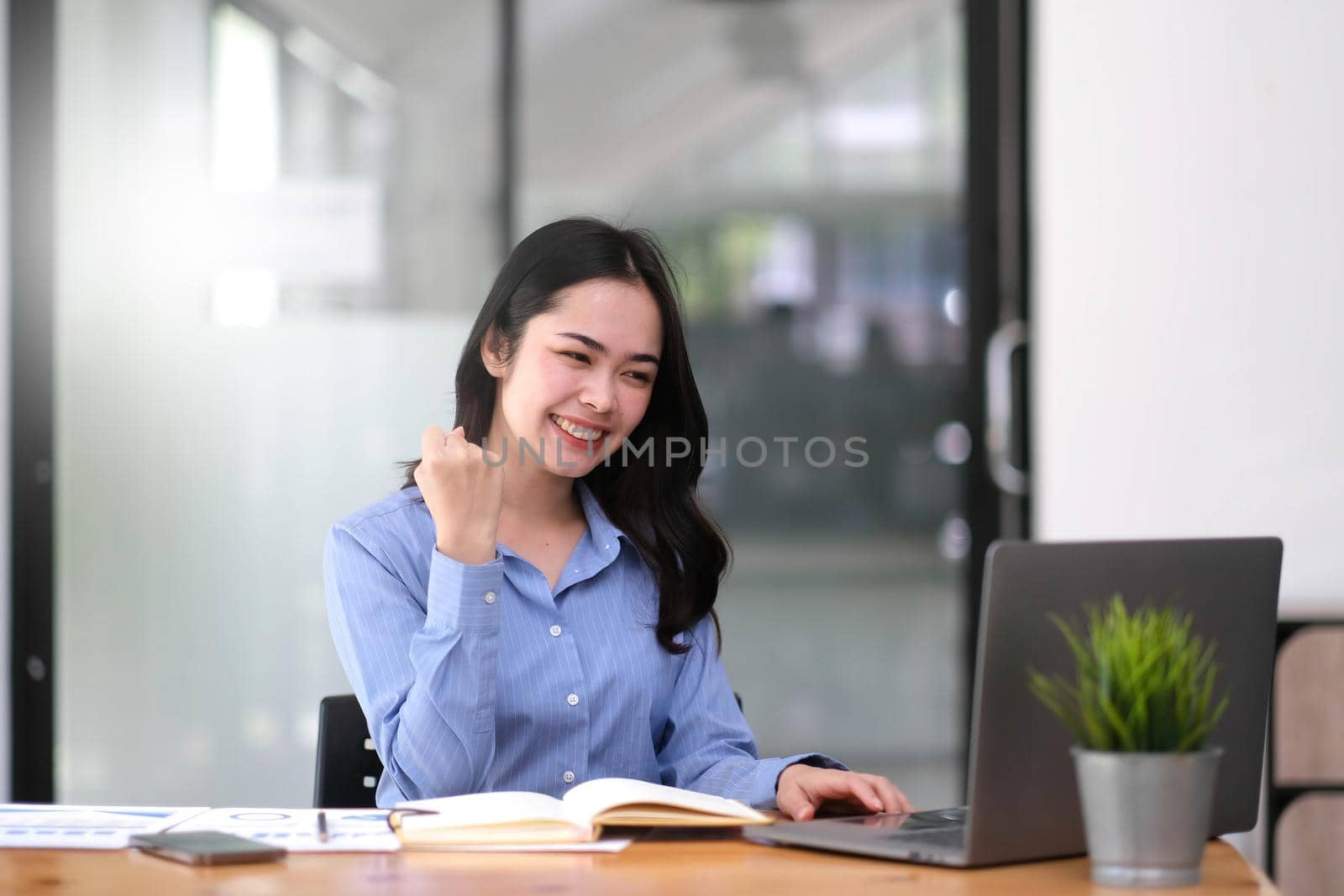 Pretty Asian businesswoman sitting on a laptop And the work came out successfully and the goal was achieved, happy and satisfied with her. by wichayada