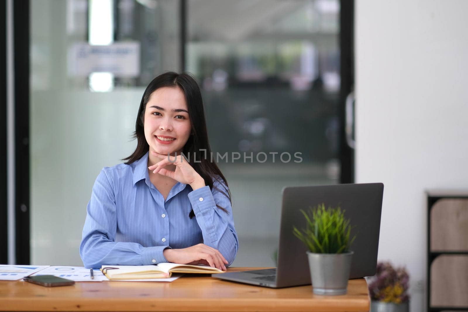Pretty young Asian businesswoman sitting in office using laptop computer..