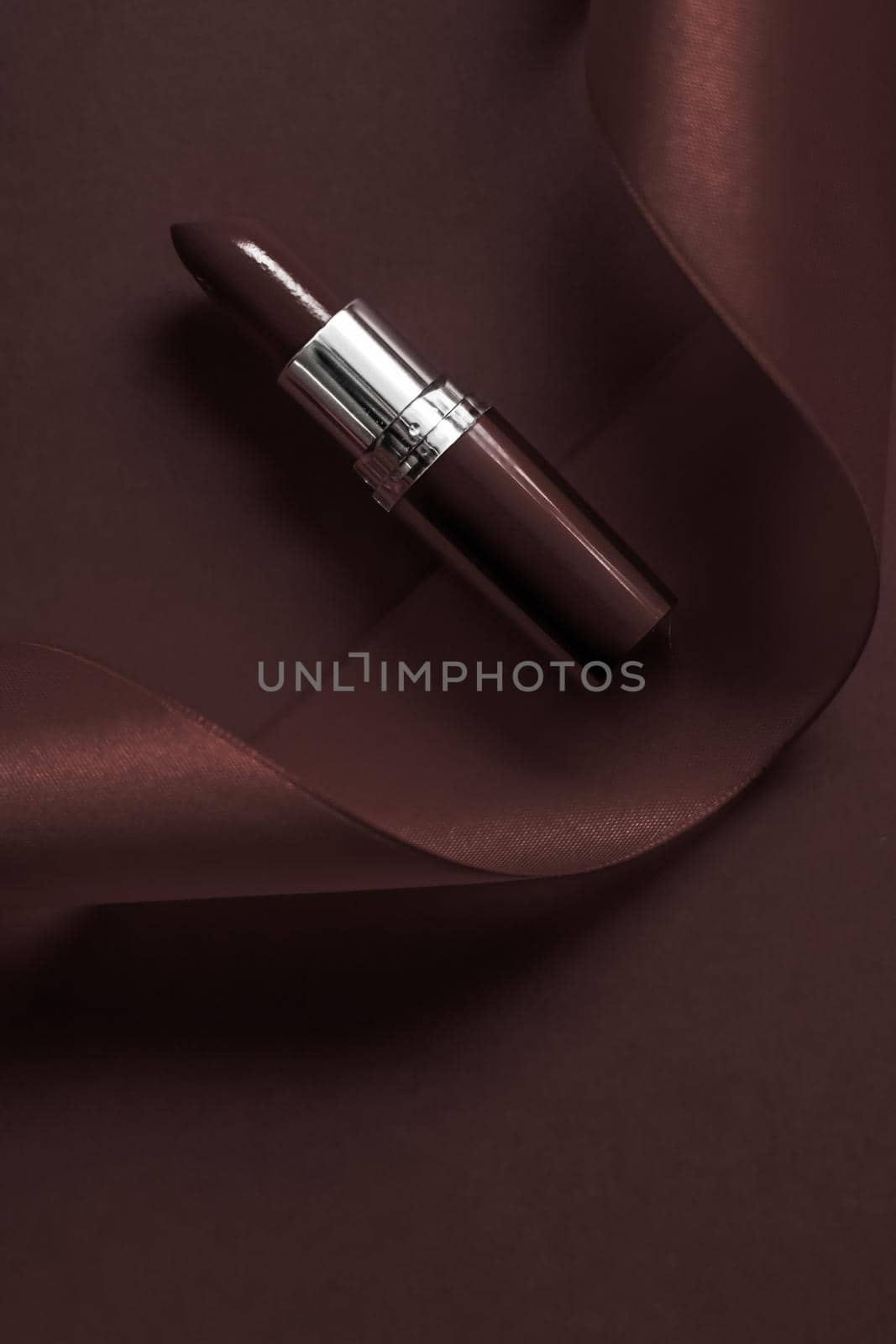 Luxury lipstick and silk ribbon on chocolate holiday background, make-up and cosmetics flatlay for beauty brand product design by Anneleven