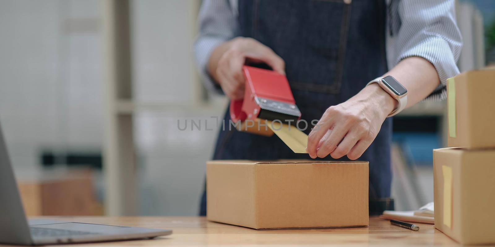 Close up online business owner prepares product for delivery to the customer. Online entrepreneur using scotch tape to seal parcel box. small business owner, SME concept..
