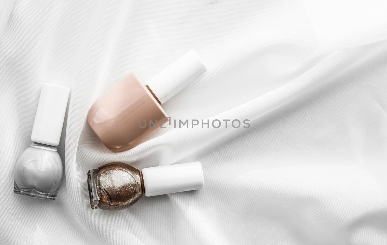 Nail polish bottles on silk background, french manicure products and nailpolish make-up cosmetics for luxury beauty brand and holiday flatlay art design by Anneleven