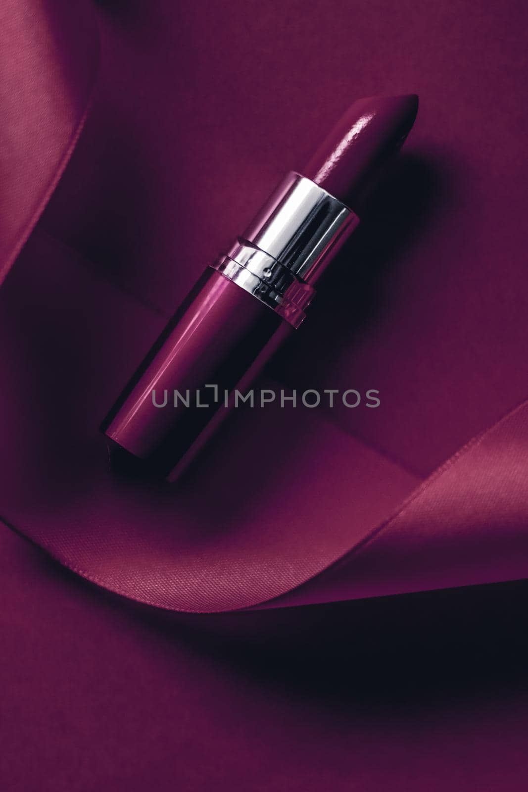 Luxury lipstick and silk ribbon on plum holiday background, make-up and cosmetics flatlay for beauty brand product design by Anneleven