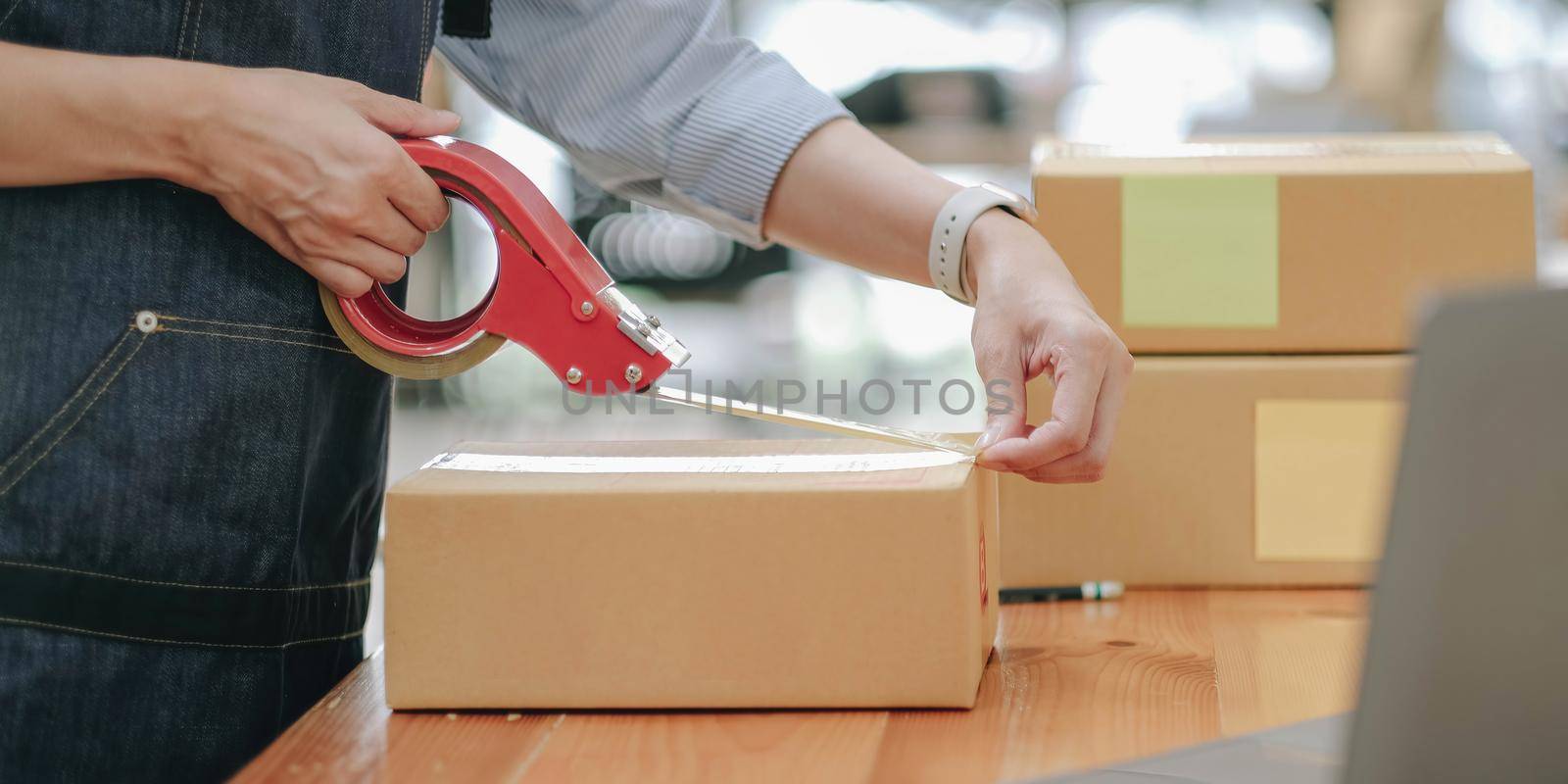 Small business entrepreneur SME, asian young woman,girl owner packing product, checking parcel for delivery to customer, using scotch tape to seal the box, working at home. Merchant online, e commerce.