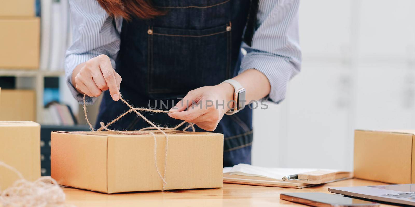 Starting small business, SME owner, female entrepreneurs are using the rope to tie boxes to pack products Order online to prepare to pack a box of goods for sale to customers, sme business idea online.