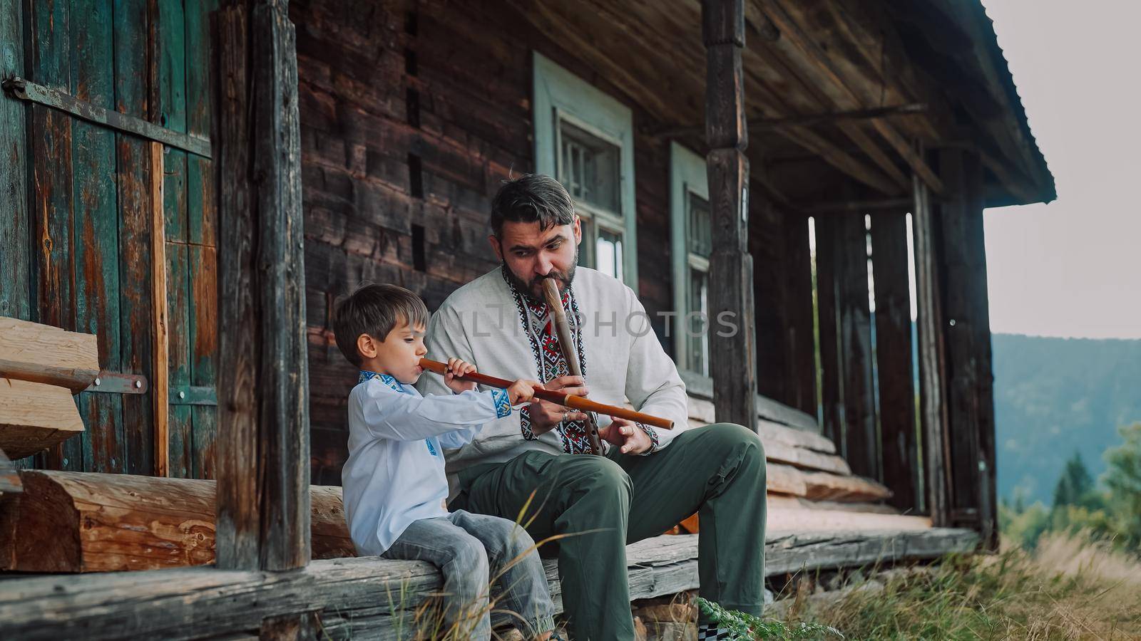 Little boy with dad playing on woodwind wooden flutes - ukrainian sopilka. Family duet, folk music concept. Father and son in traditional embroidered shirts. High quality