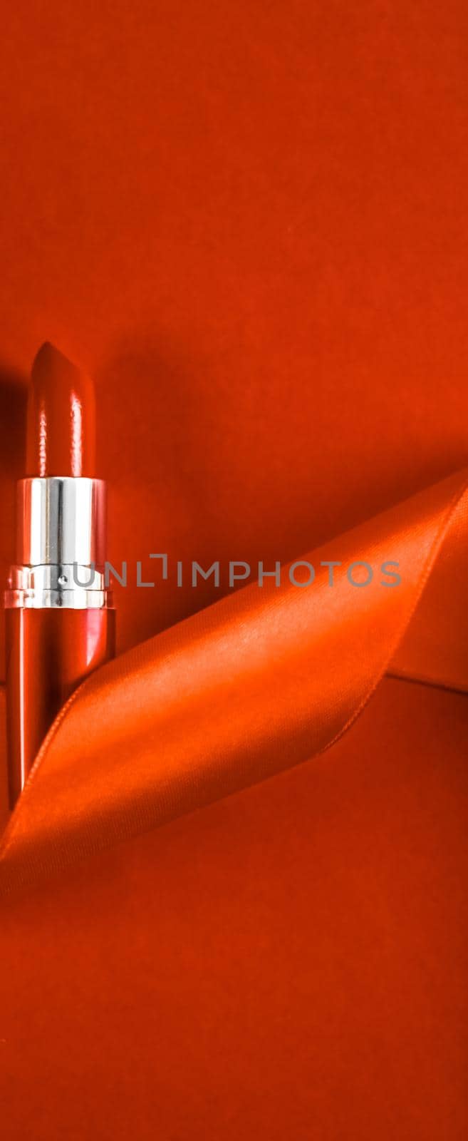 Luxury lipstick and silk ribbon on orange holiday background, make-up and cosmetics flatlay for beauty brand product design by Anneleven