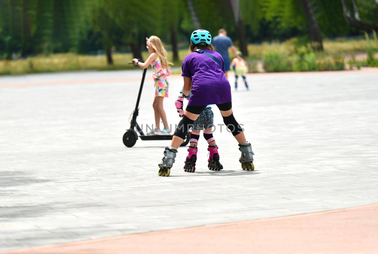 Young mother and her little daughter rollerskating in summer park. happy family have fun. High quality photo