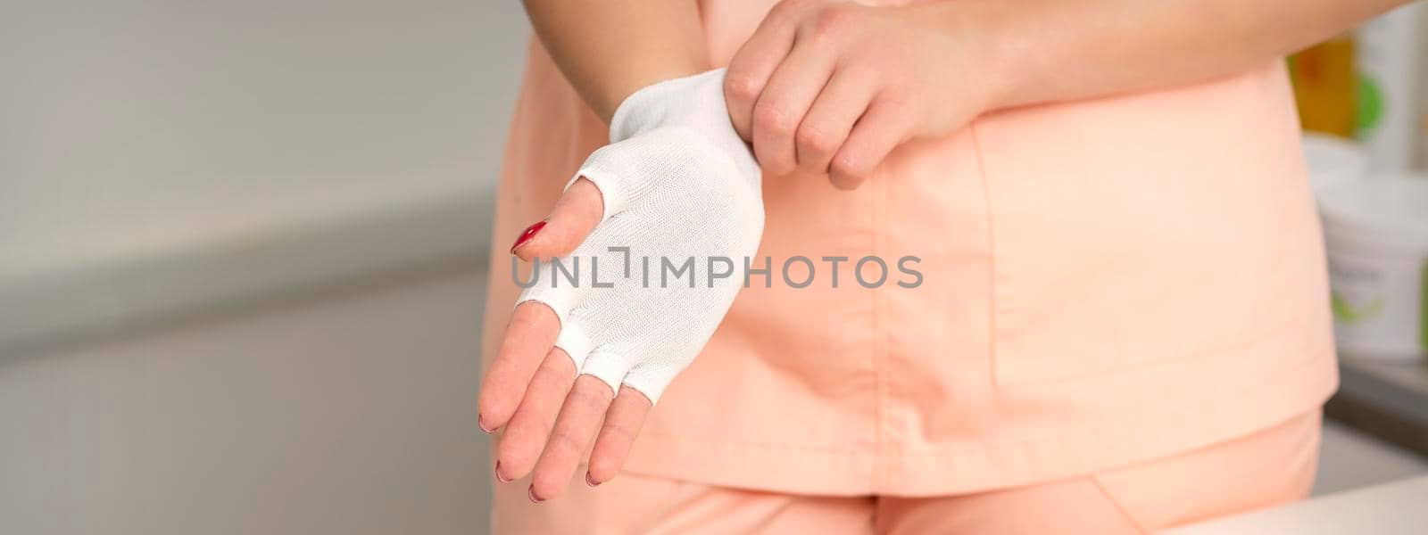 Cosmetologist in workwear wearing white bamboo fingerless gloves on her hands. by okskukuruza