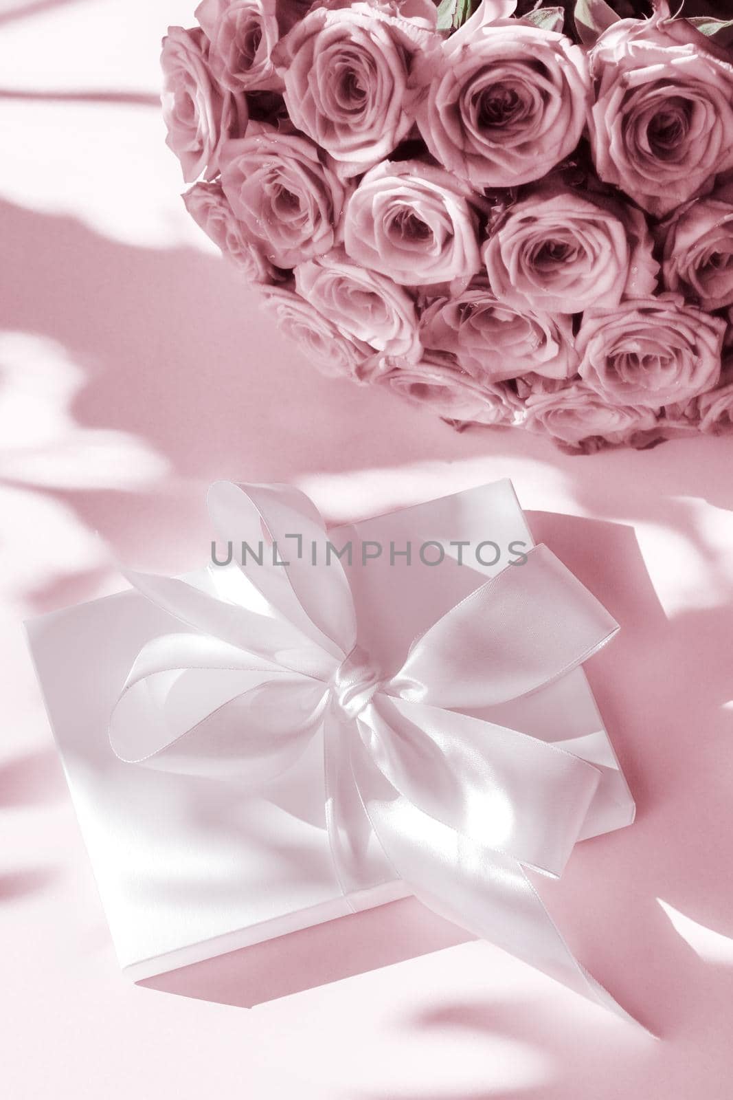 Happy holidays, luxe shopping and love gifts concept - Luxury holiday silk gift box and bouquet of roses on blush pink background, romantic surprise and flowers as birthday or Valentines Day present