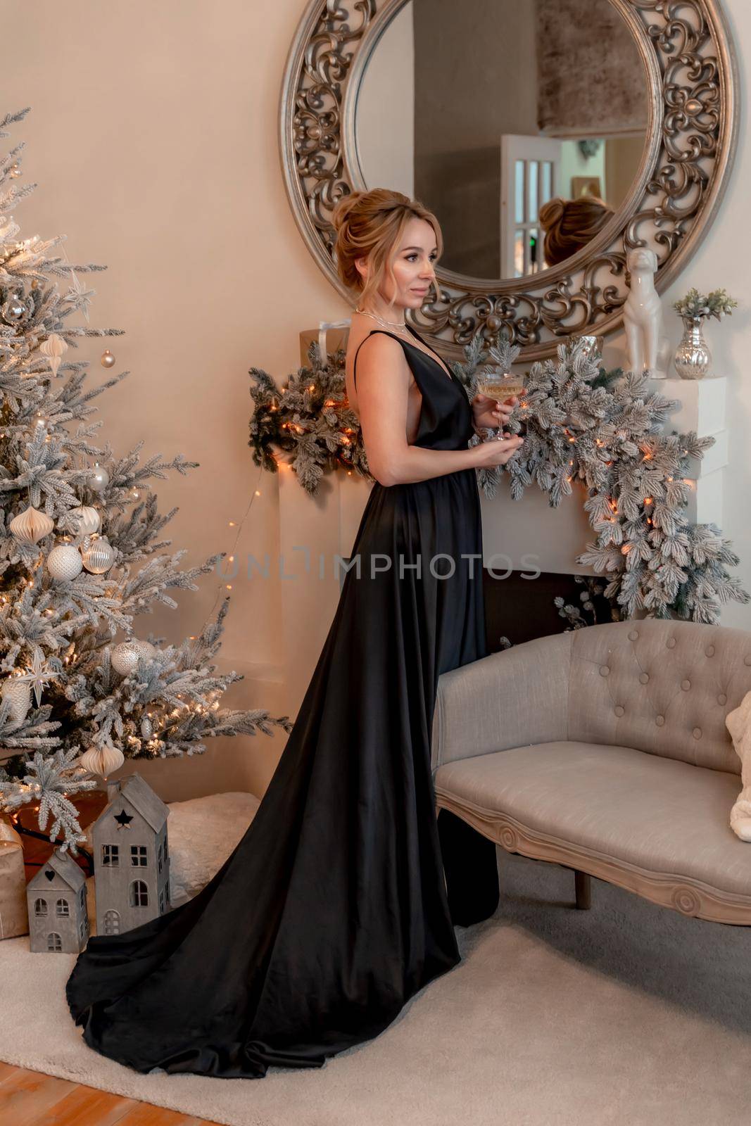 Portrait of a wealthy mature woman with evening make-up and hairstyle posing in a black dress on the background of the Christmas room. Luxurious lifestyle. Christmas holidays concept by Matiunina