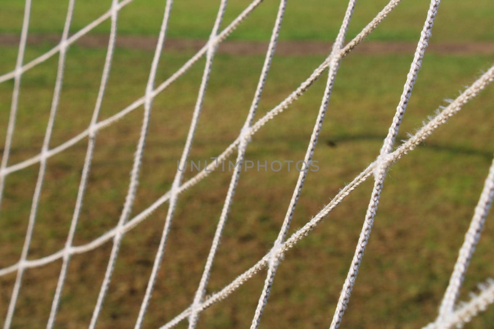 The grid from the old football goal close-up on the background of the football field.
