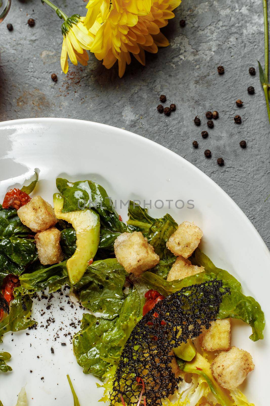 Avocado salad with baby spinach and pomegranate on a black plate on a slate,stone or concrete background.Top view with copy space by UcheaD