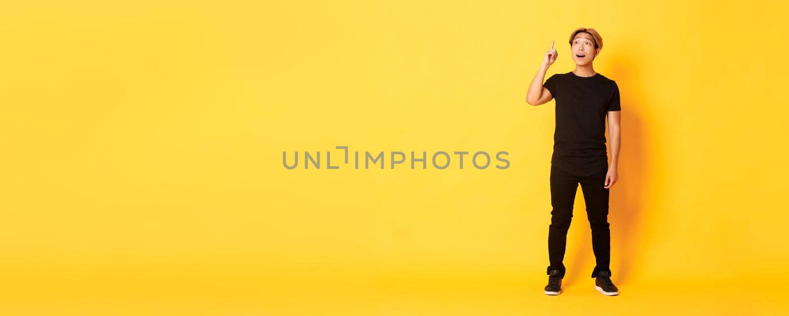 Full-length of thoughtful handsome asian man, raising finger up, have good idea, standing yellow background by Benzoix