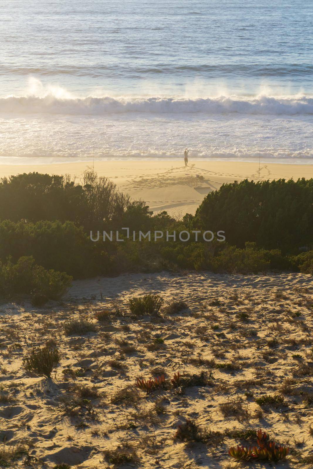 Ocean beach with a lone figure of a fisherman on the shore