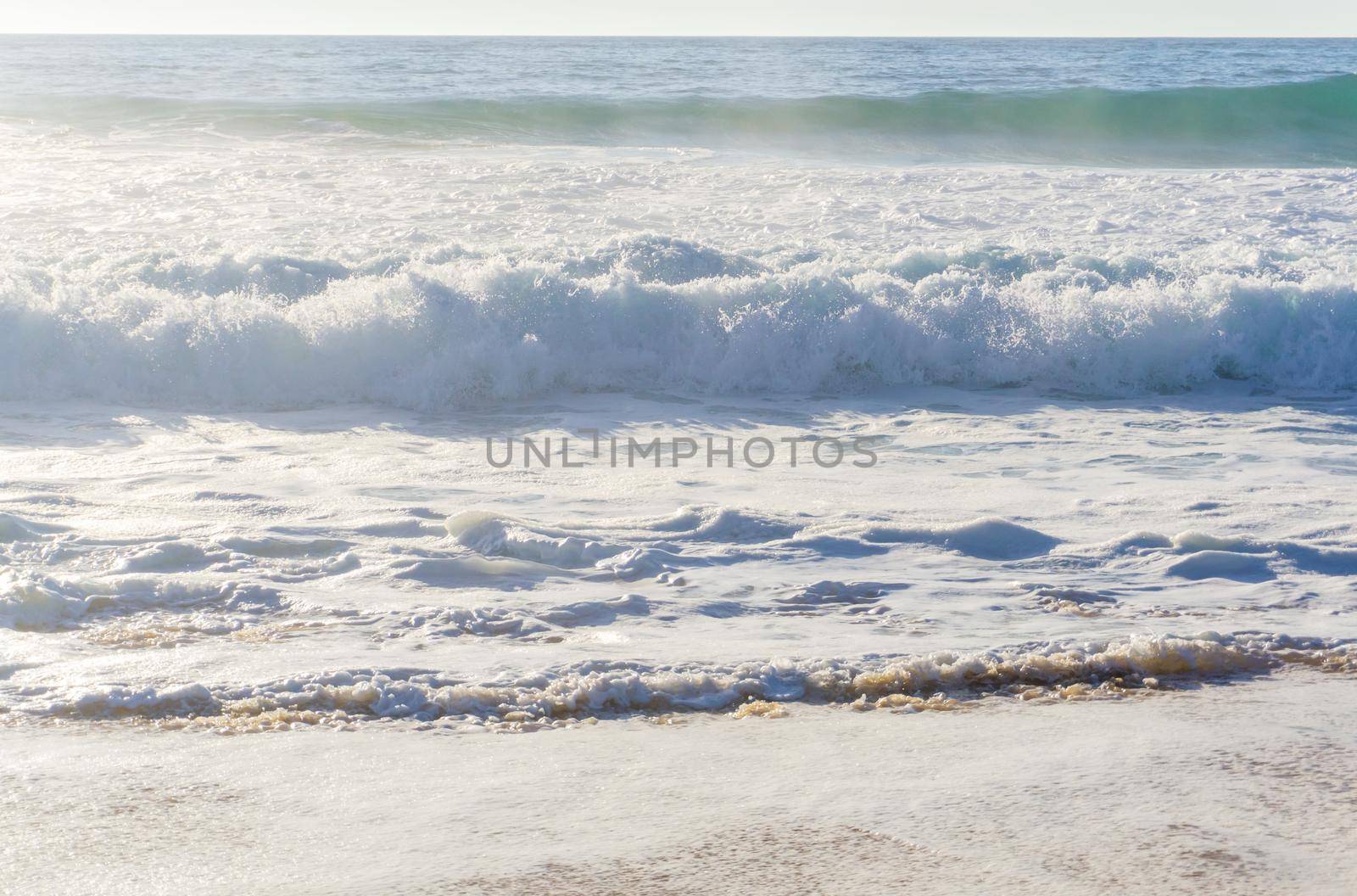 Ocean waves with white foam on a sunny day background