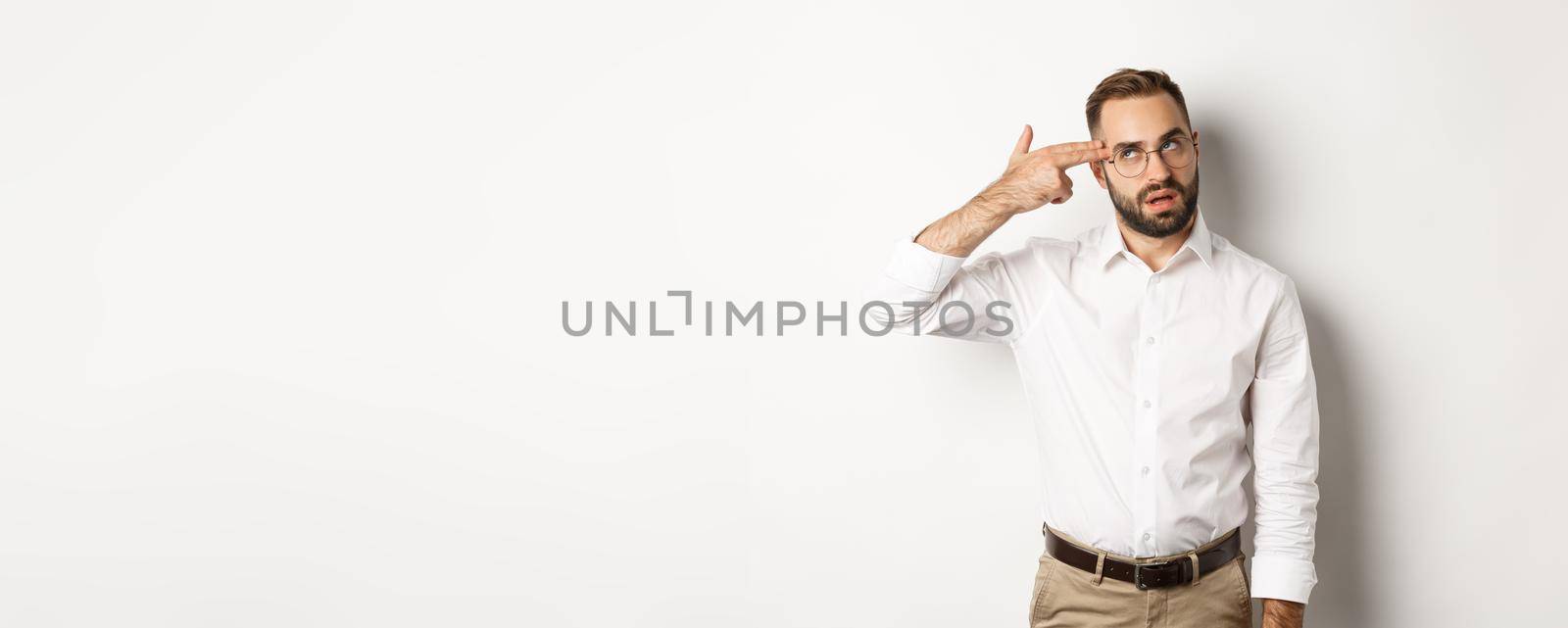 Annoyed man making shooting in head and roll eyes, standing distressed over white background by Benzoix