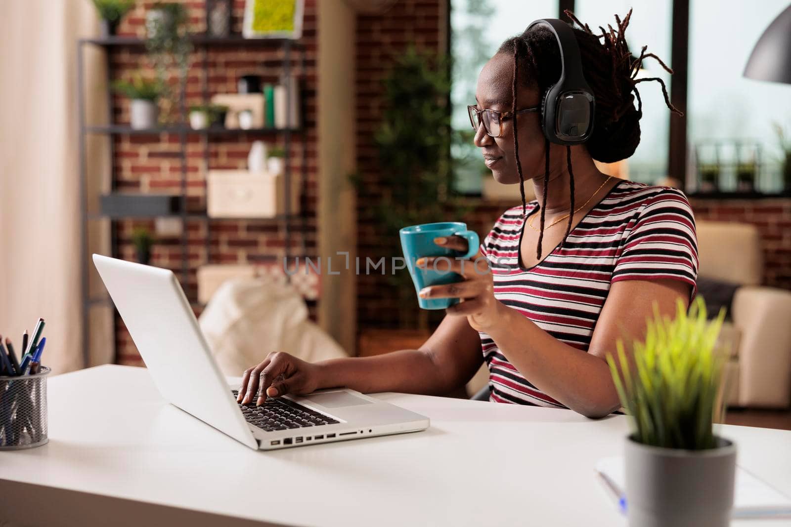 Woman in wireless headphones watching movie online on laptop by DCStudio