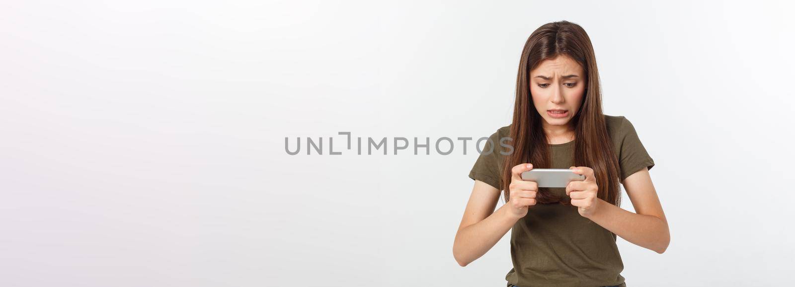 Happy attractive brunette girl joying win in video game on smartphone, isolated over grey background.