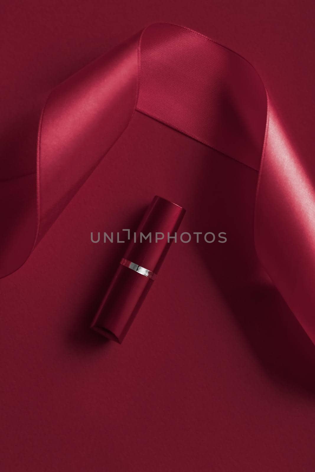 Cosmetic branding, glamour lip gloss and shopping sale concept - Luxury lipstick and silk ribbon on maroon holiday background, make-up and cosmetics flatlay for beauty brand product design