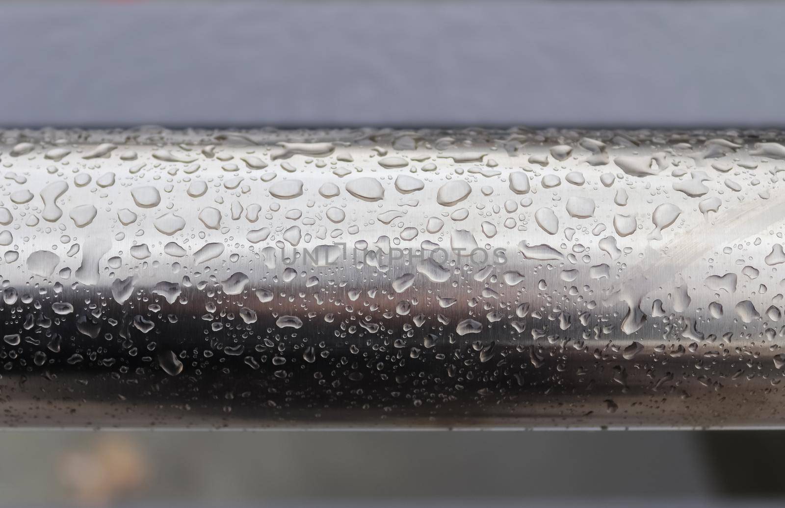 Rain drops on a black metallic surface in a closeup view