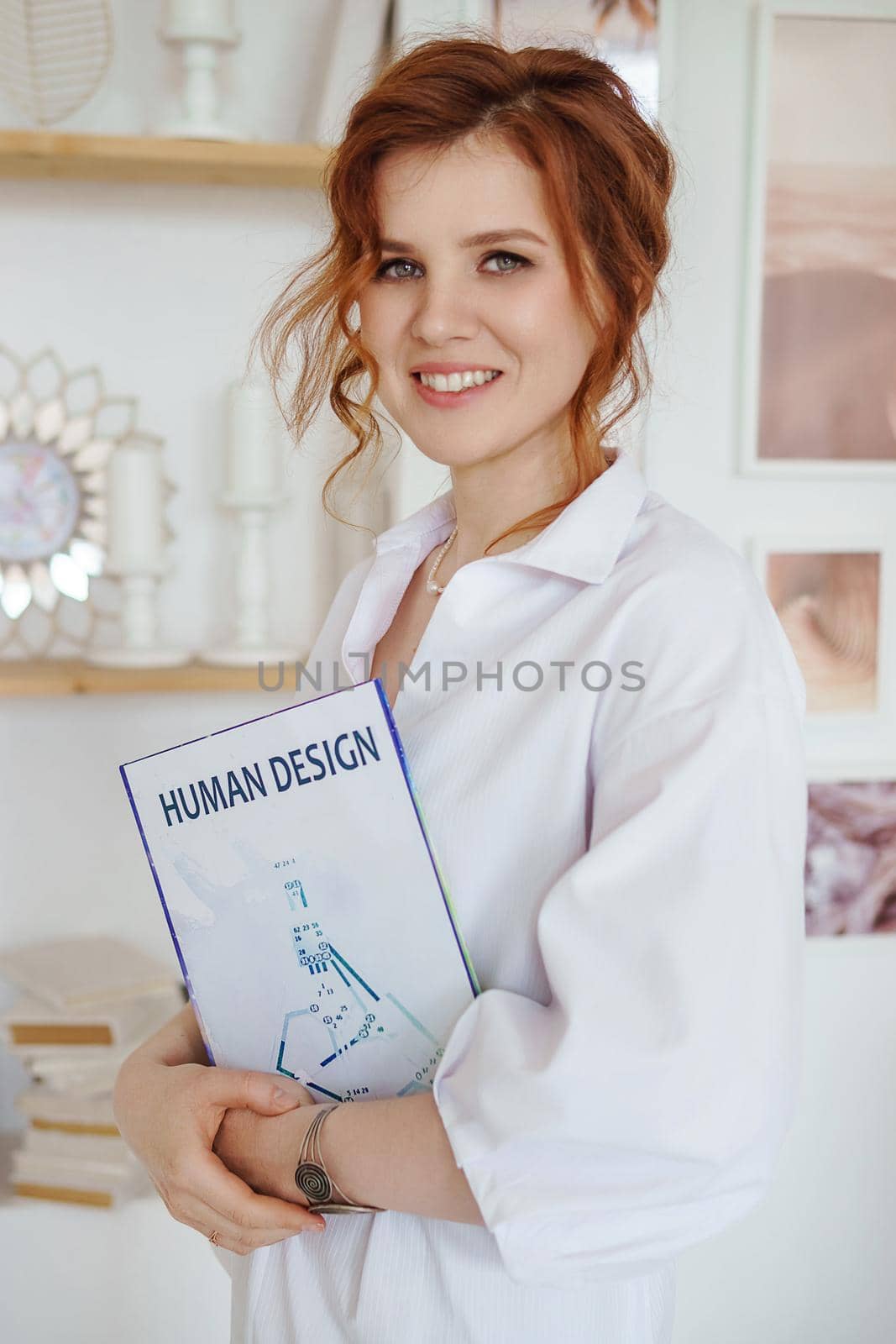 A business woman with a book on Human Design in her hands. A human design specialist works at home. Working at home during the epidemic