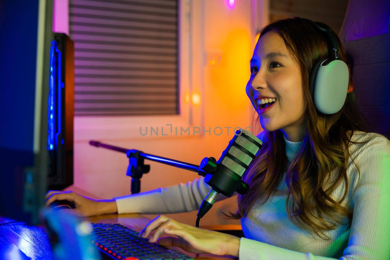 woman wear headphones playing video games online on computer she live stream and chat with fans by Sorapop