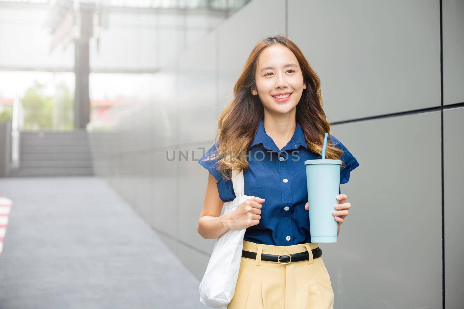 business woman confident smiling with cloth bag holding steel thermos tumbler mug water glass by Sorapop
