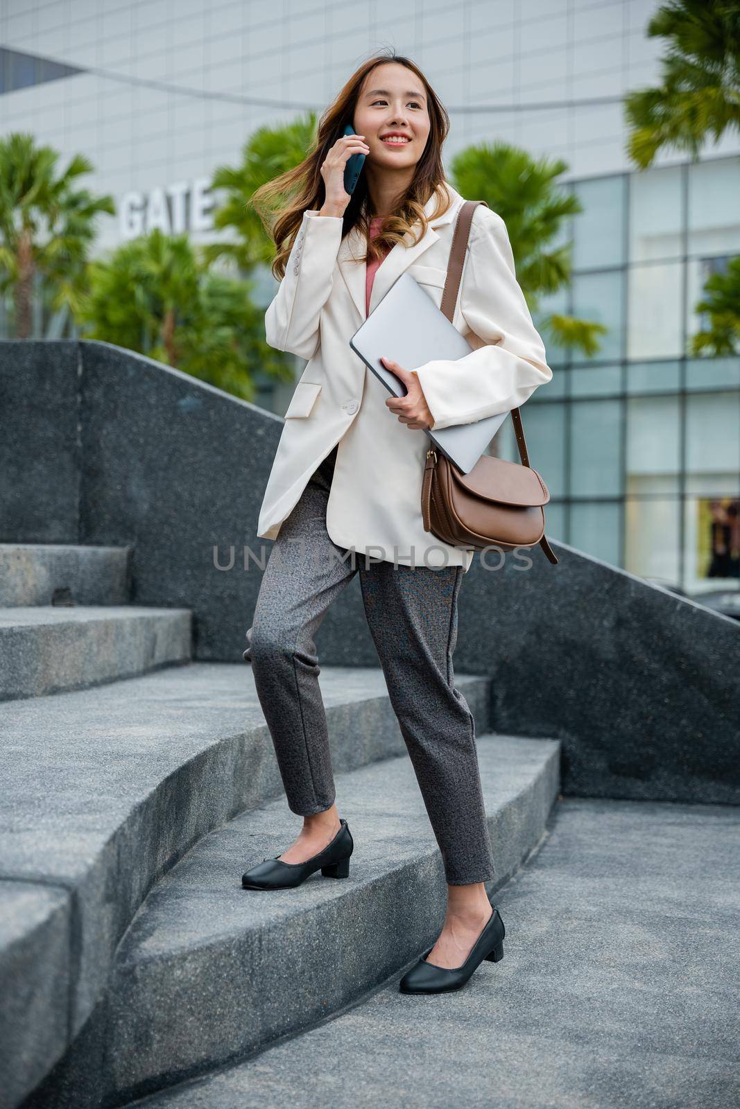 Stepping going up stairs in city, Business woman hold laptop computer talking mobile phone she hurry up walking on stairway, rush hour to work in office a hurry in morning, step up success, Full body