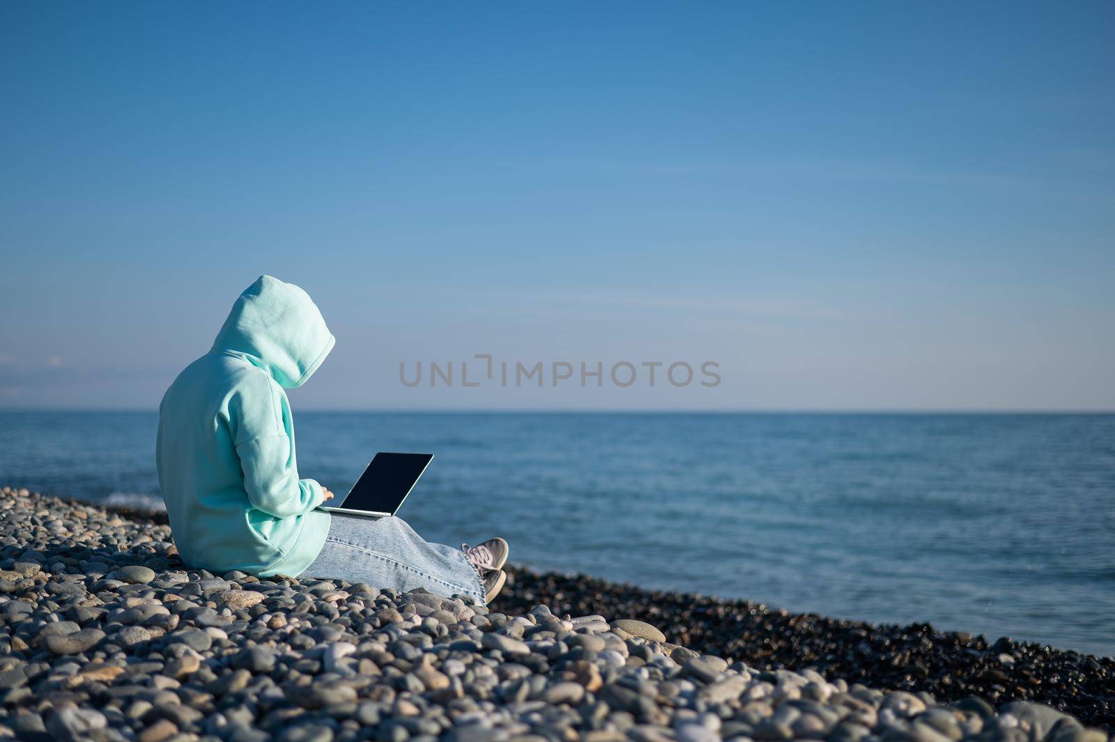 Caucasian woman working freelance on laptop on the beach