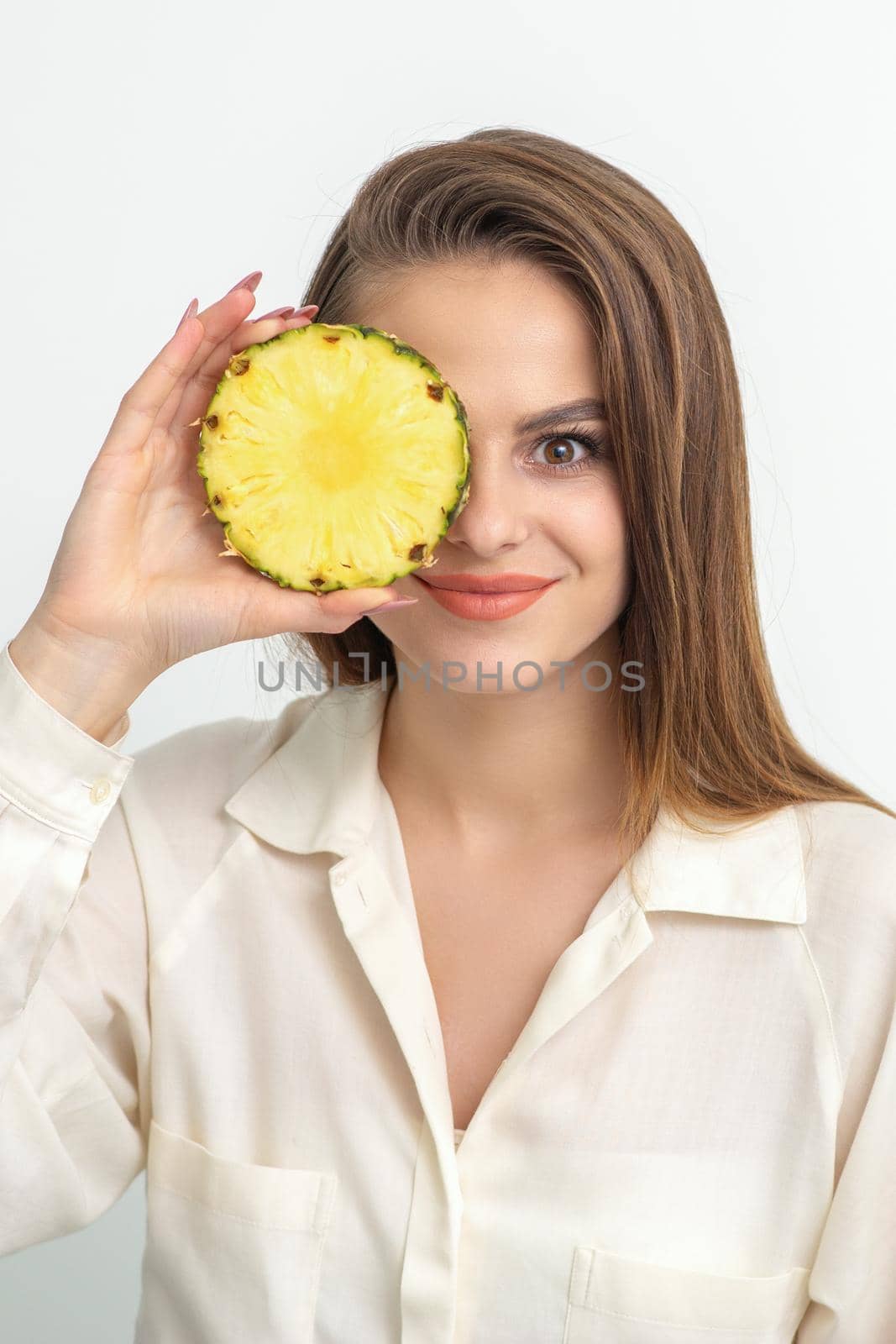 Attractive pretty nice young caucasian woman hold sliced pineapple covering her eye isolated on white color background. by okskukuruza