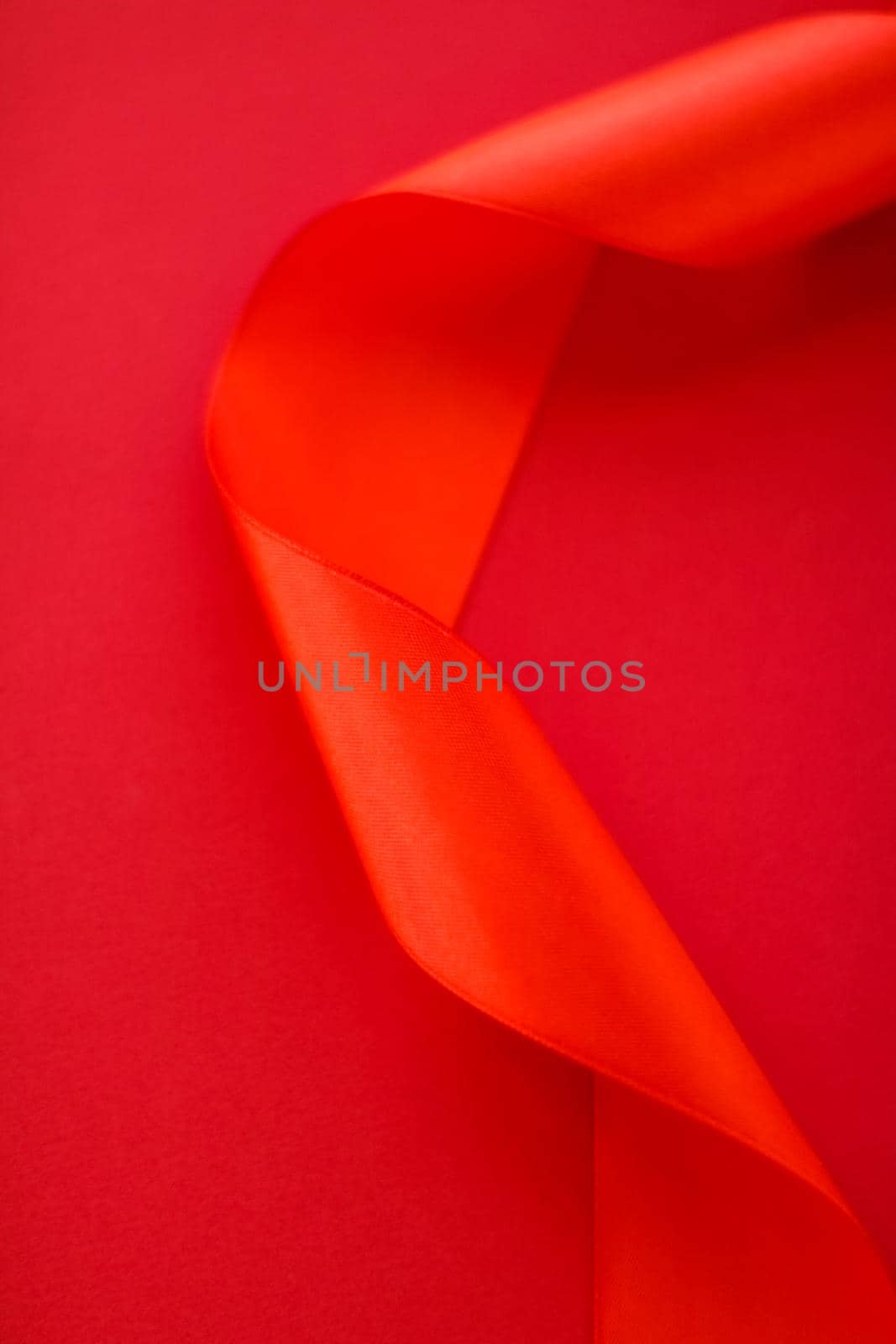 Branding, holidays and luxe brands concept - Abstract curly silk ribbon on red background, exclusive luxury brand design for holiday sale product promotion and glamour art invitation card backdrop