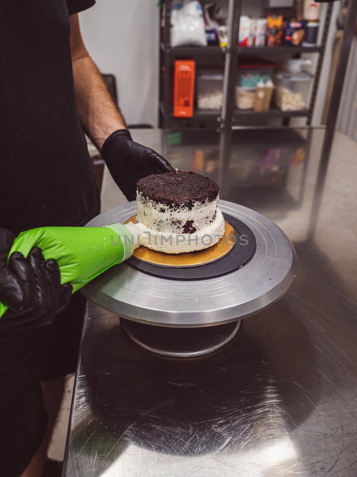decorator applying buttercream to frosted cake with bag full of cream