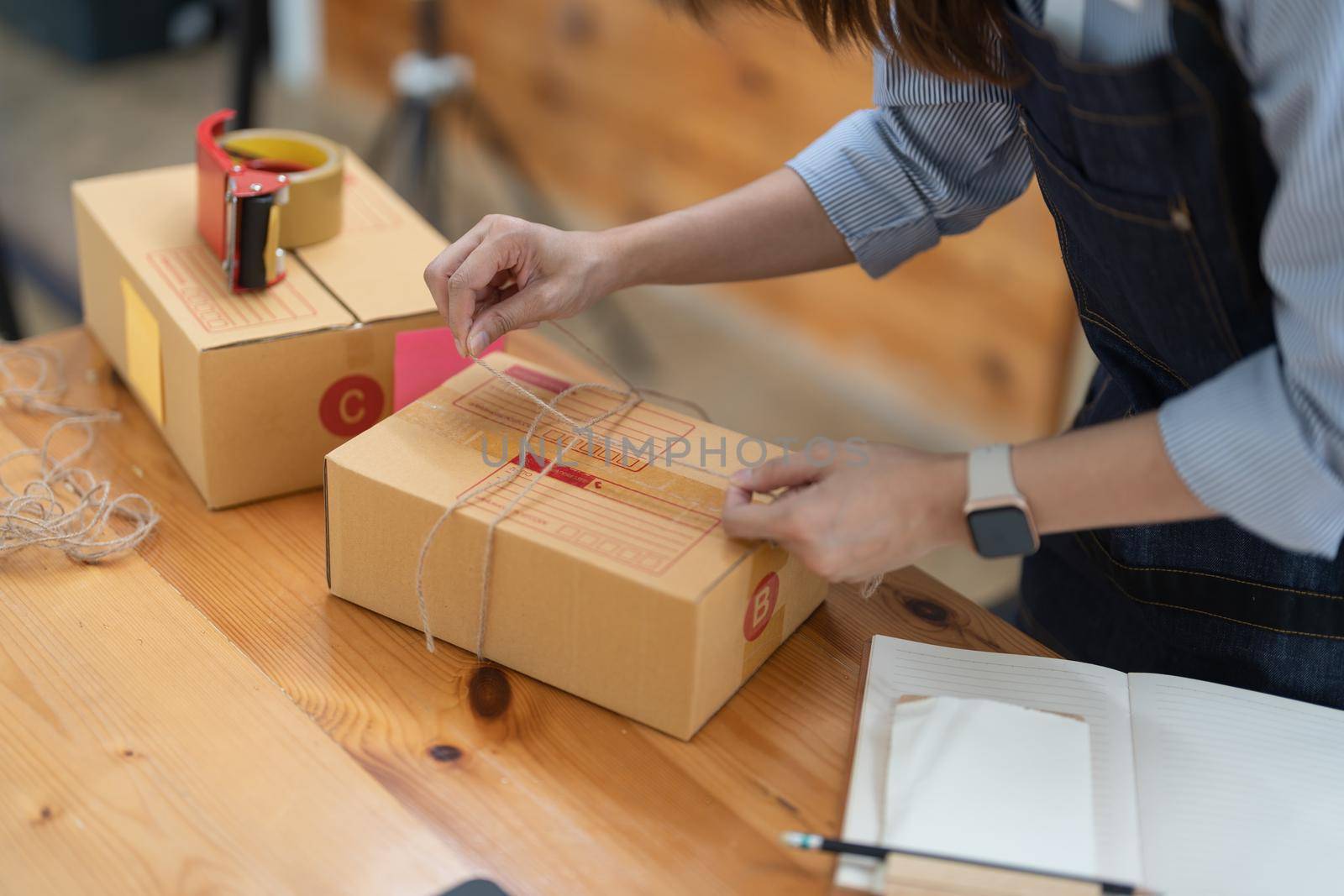 Young small business owner packing deliveries in modern office and storage space.