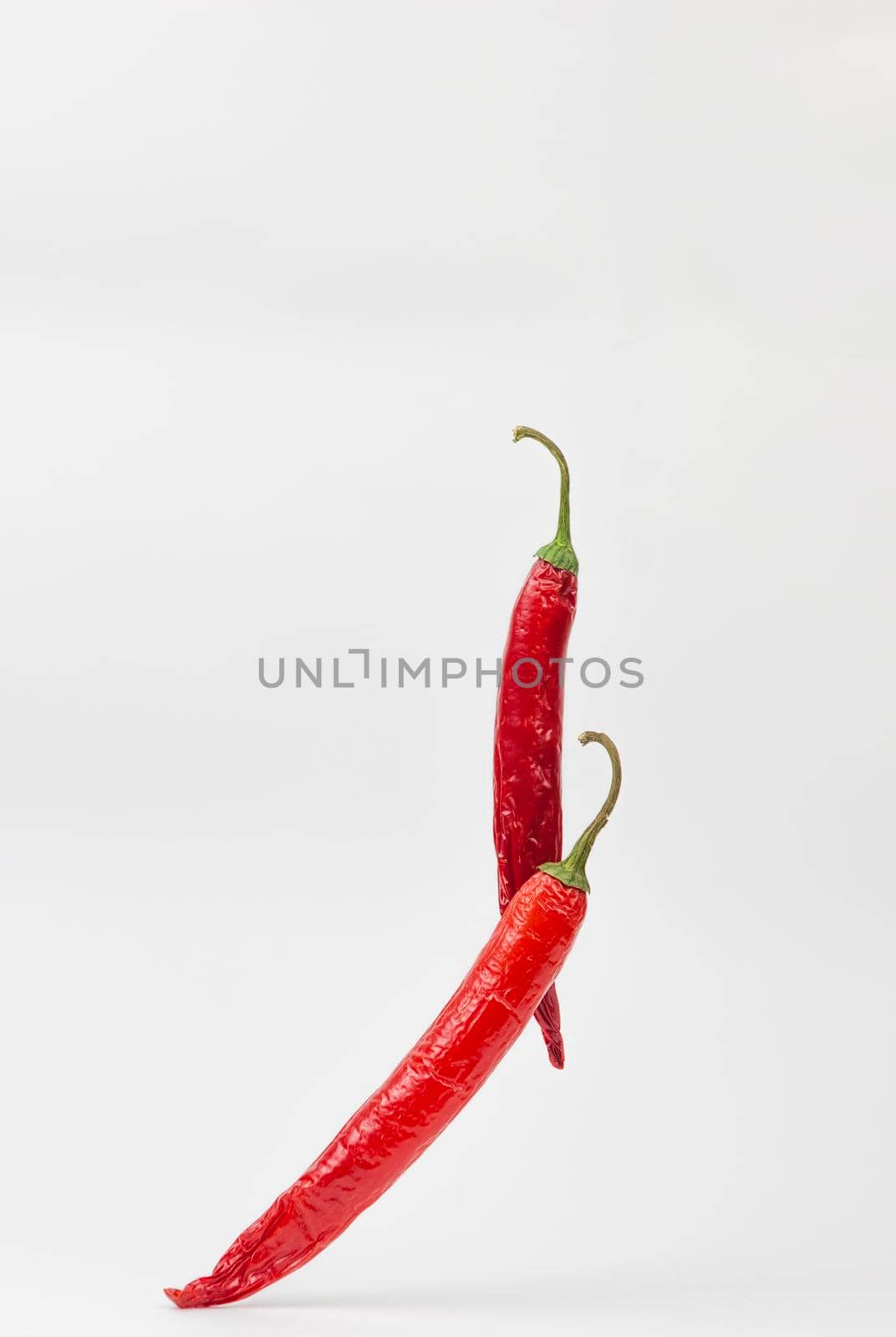 Falling red chili or chilli pepper on white background