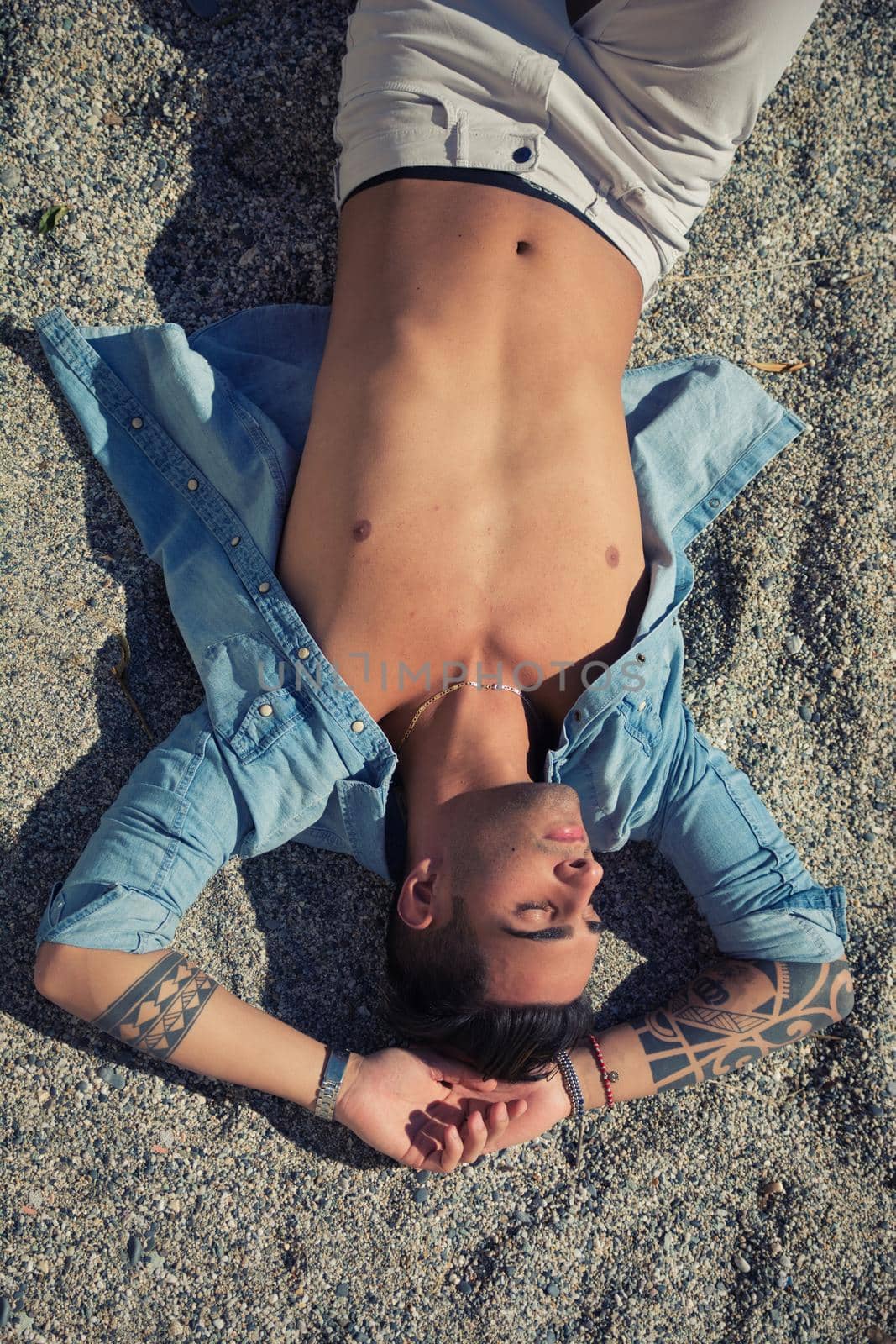 Handsome man laying on surfboard at beach by artofphoto