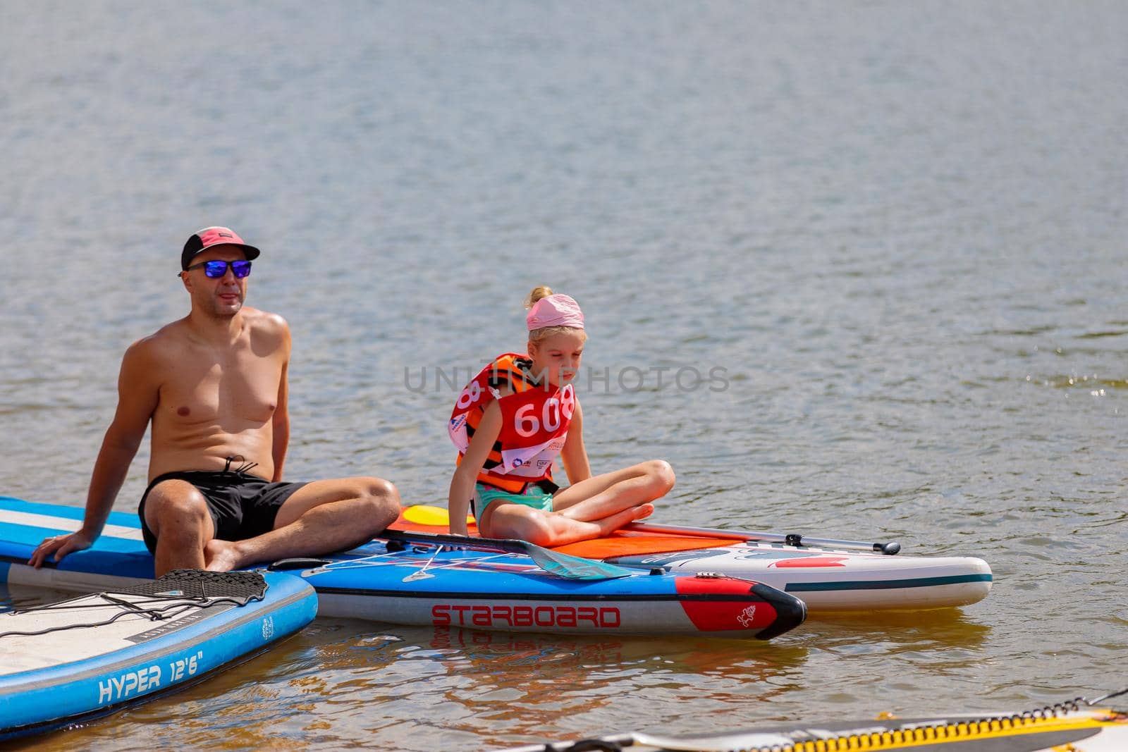 A child swims on a surfboard, pushing off with a paddle. Paddleboarding. Russia Zelenograd 14 August 2021