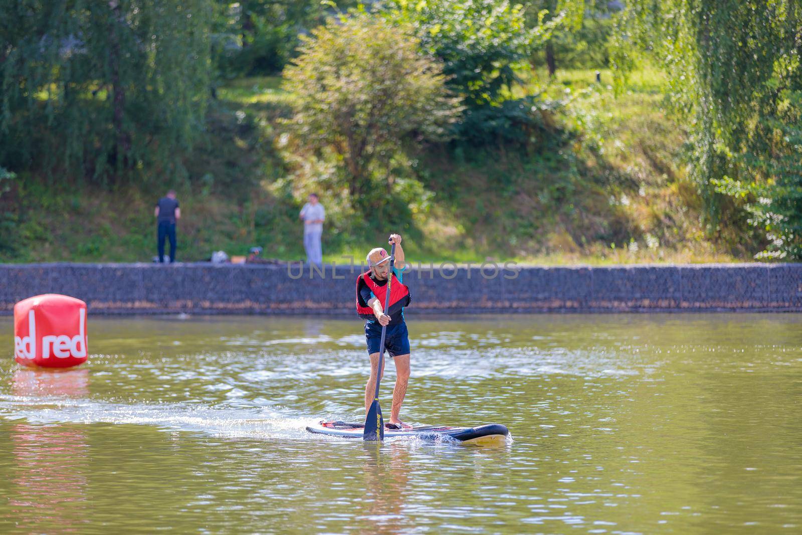 A man swims on a surfboard, pushing off with an oar. Paddleboarding. Russia Zelenograd 14 August 2021