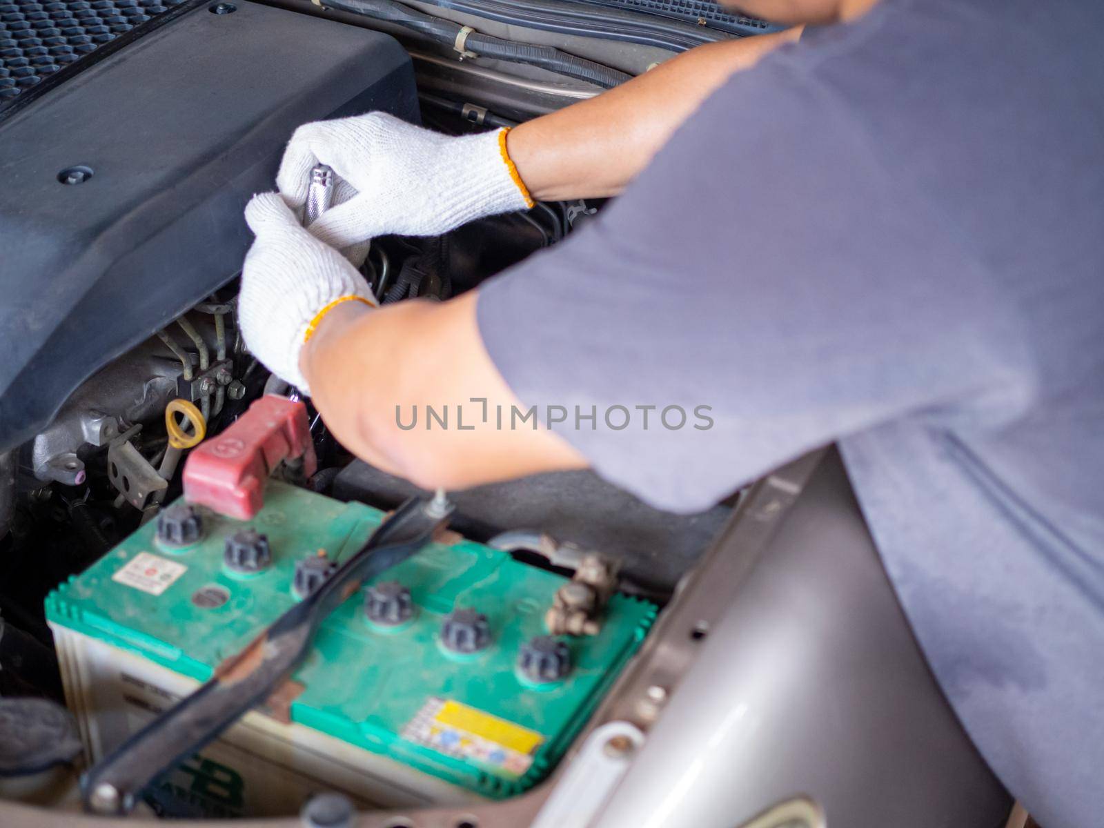 Mechanic holding a block wrench handle while fixing a car. by Unimages2527