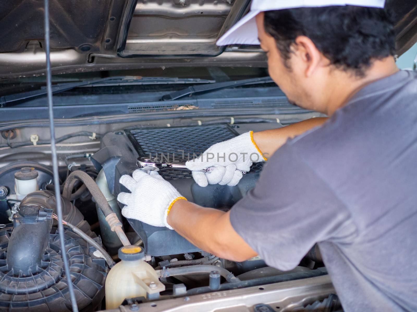 Mechanic holding a block wrench handle while fixing a car.