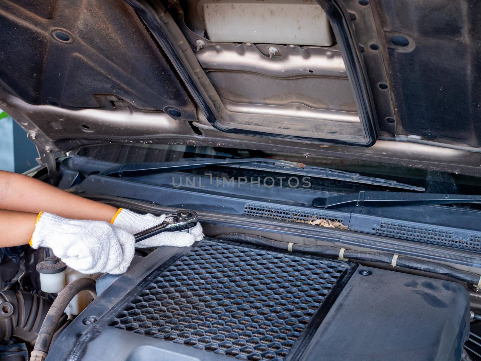 Mechanic holding a block wrench handle while fixing a car.