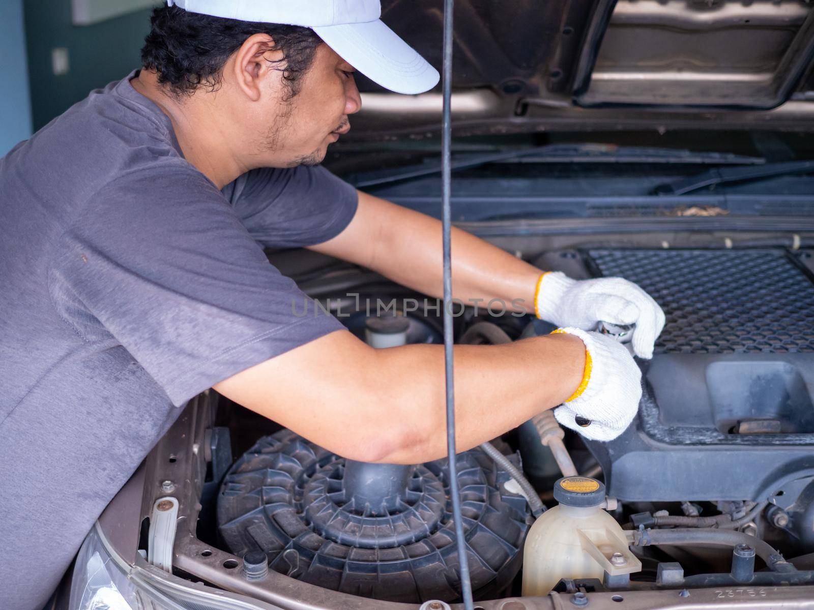 Mechanic holding a block wrench handle while fixing a car.