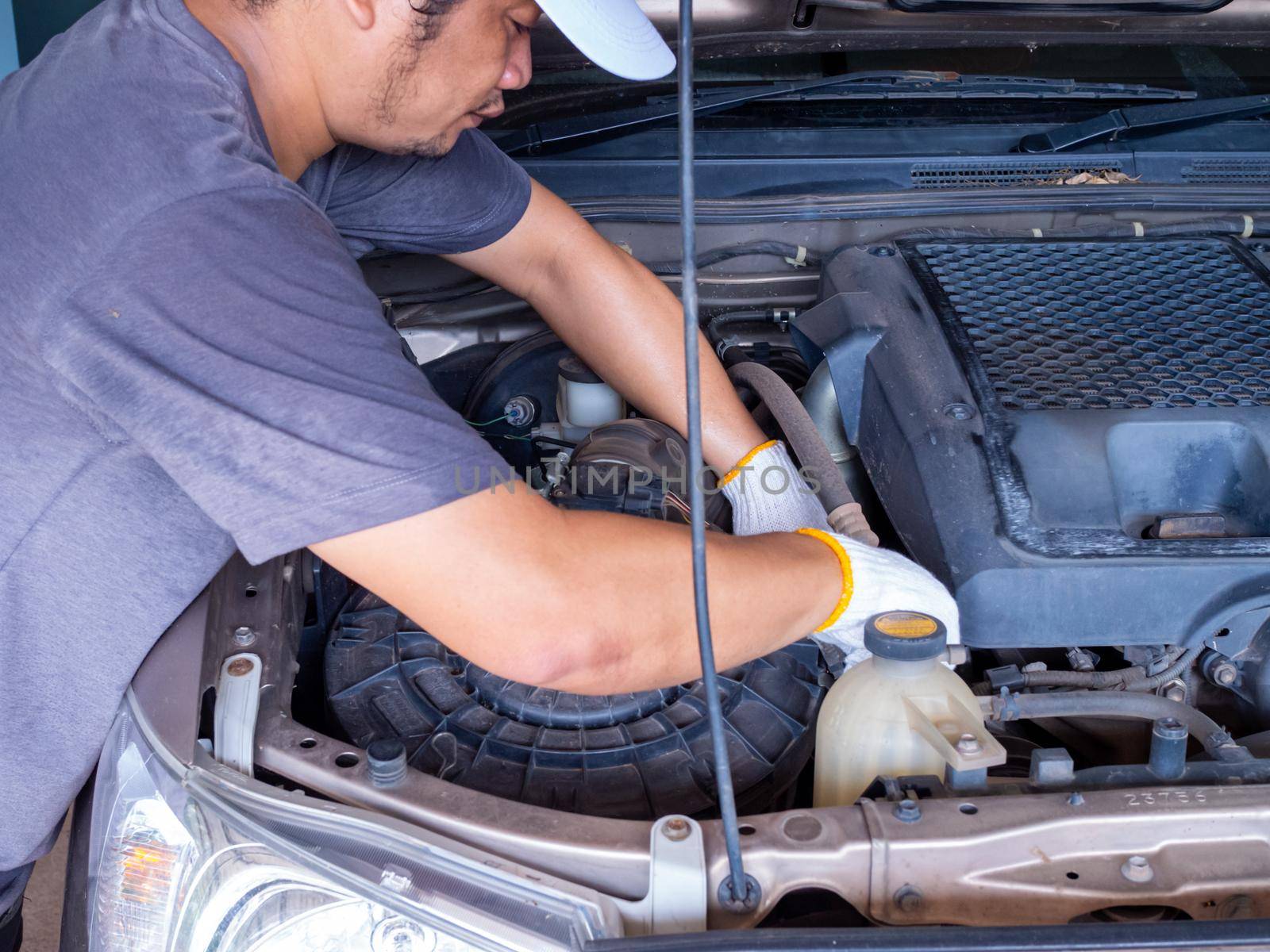 Mechanic holding a block wrench handle while fixing a car. by Unimages2527