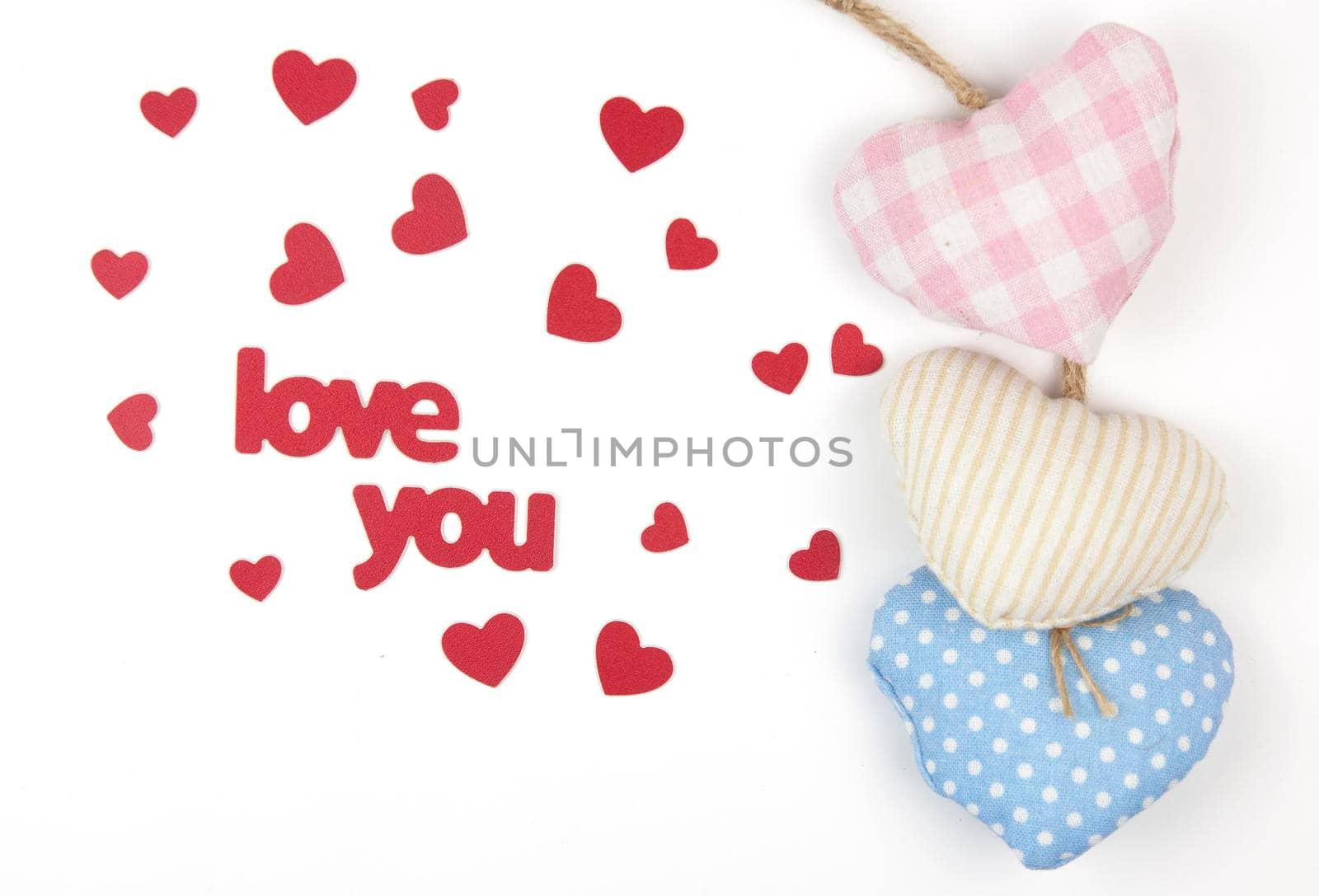 Valentine's day card. Top view cute composition with handmade fabric hearts on white paper background. Happy birthday or anniversary congratulation. Romantic message template with copy space.